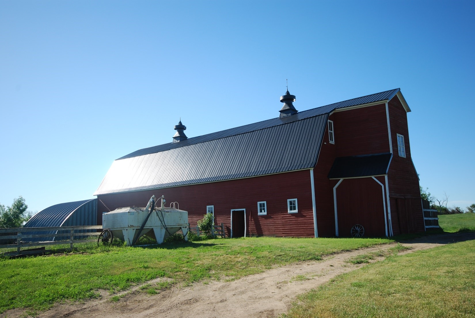 Red barn with white trim and dark gray roof.